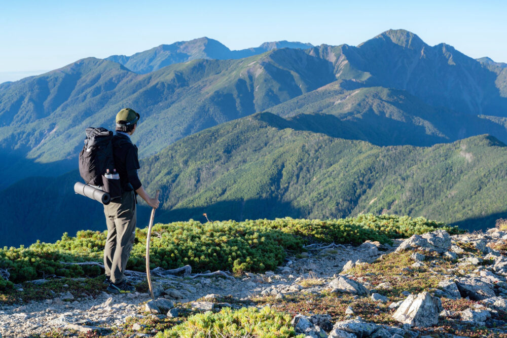 木のつえを持ち、登山をする大塩様