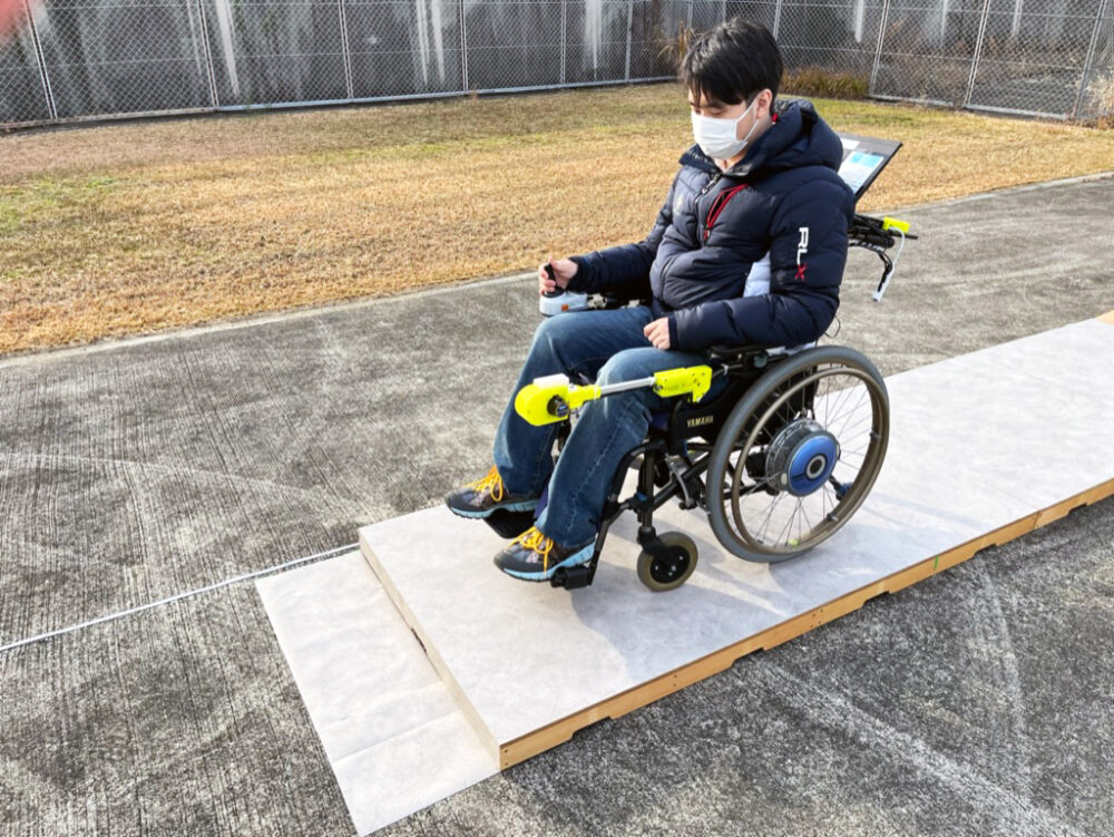 低い木製の段の上で、車いすに座る男性