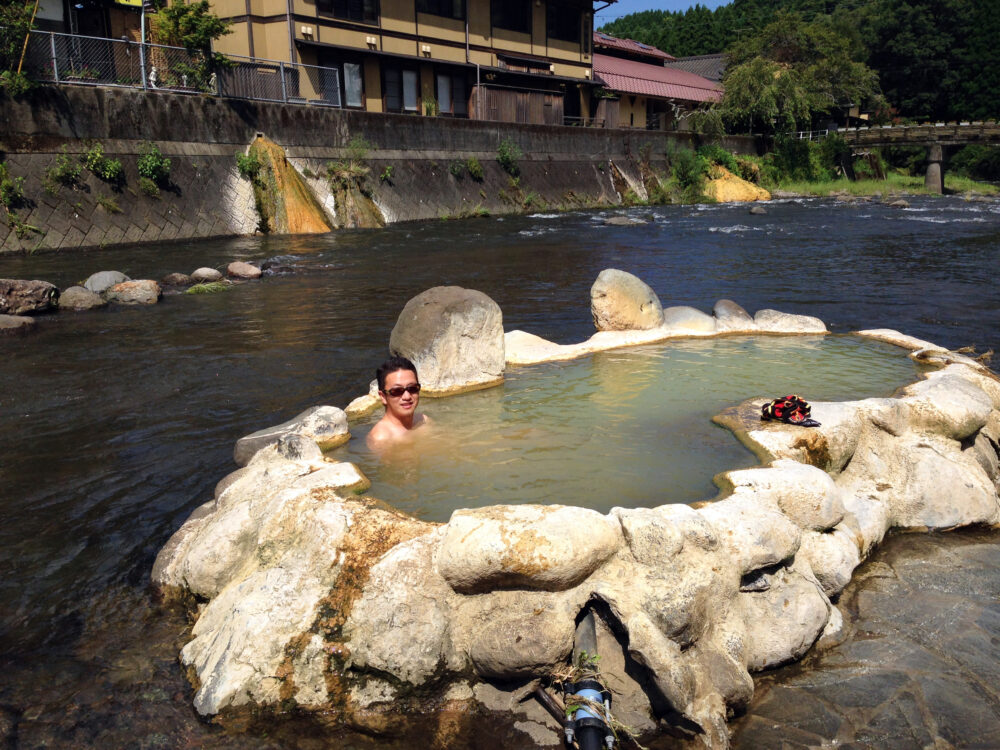 九州の川の中にある温泉を楽しむ松本先生