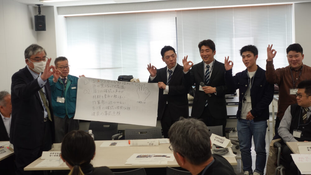 安全講習のグループ発表の様子。親指と人差し指で丸をつくって、考案した合言葉「ご安全に!!」のポーズをしています