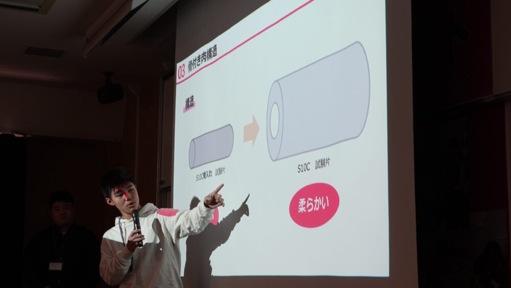 プレゼンテーションの様子。佐世保高専チームは、外は固くて中は柔らかいという「骨付き肉構造」の加工を施して強靭化を試みました。