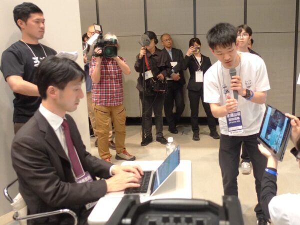 豊田高専「Kanro AI」の技術審査会の様子。本選技術審査員の佐々木雄一さん(SpiralAI株式会社 CEO)が審査中