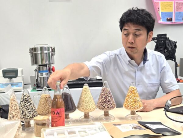 在来作物を活用した商品を紹介中の森田先生。手にされているのは、もちとうきびを原料としたクラフトビール「MOCHI」（藤居醸造との共同開発）。