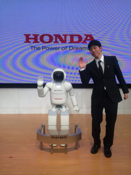 Hondaに入社された頃の板井さん。二足歩行ロボット「ASIMO」と一緒に