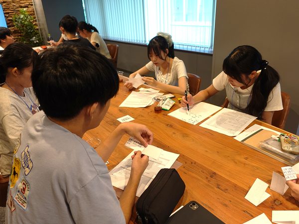 情報の非対称性ワークの様子。各学生に配られたカードに記載されている情報を“口頭のみ”でグループ内に共有し、架空の自宅から面接会場までの最短ルートを検討しました